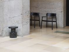 two chairs sitting next to each other in front of a wall with marble tiles on it