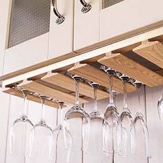 several wine glasses are hanging on the wall next to some cabinets and cupboards,