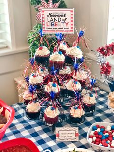 a table topped with cupcakes and desserts covered in red white and blue frosting