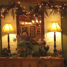 a dresser with two lamps on top of it next to a mirror and some lights