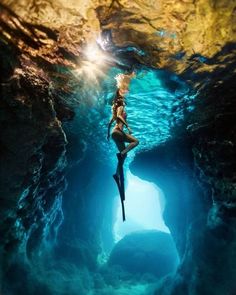 a woman is floating in the middle of a cave