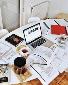 a table topped with lots of papers and a laptop computer sitting on top of it