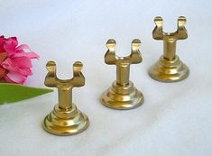 three brass candlesticks sitting next to a pink flower