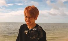 a woman holding a camera in front of the ocean