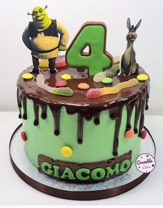 a green birthday cake with chocolate frosting and cartoon characters on top, including the number four