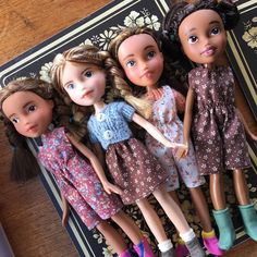 four dolls laying on top of each other in front of a book with an open notebook behind them