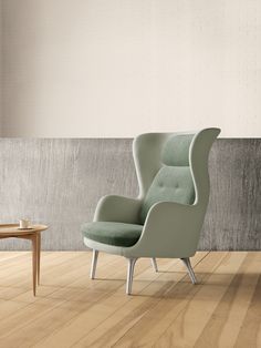 a green chair sitting on top of a hard wood floor next to a wooden table