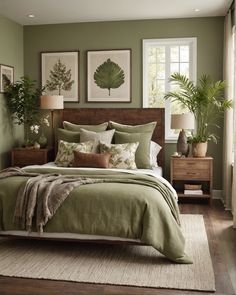 a bed with green sheets and pillows in a bedroom next to two plants on the wall