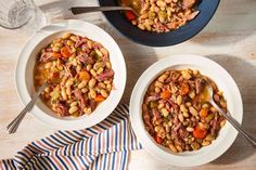 two bowls filled with beans and meat on top of a table