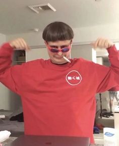 a young man with sunglasses on his head is standing in front of a laptop