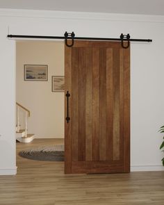 an open wooden door in a white room with wood flooring and rug on the floor