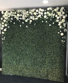 the wall is covered with white flowers and greenery