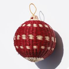 a red and white ornament hanging from a string on a white wall,