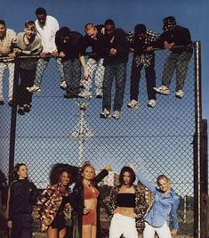 a group of young people standing next to each other on top of a metal fence