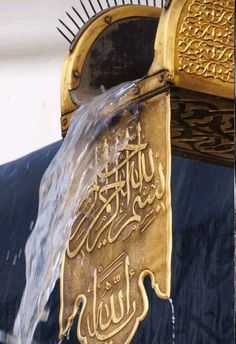 a close up of a fountain with water coming out of it and arabic writing on the side