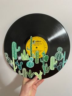 a hand holding up a vinyl record with cactus and cacti on it