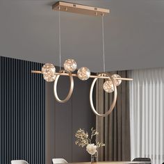 a modern chandelier hanging over a dining room table with chairs and vases