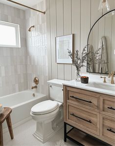 a white toilet sitting next to a bath tub in a bathroom under a mirror above a sink