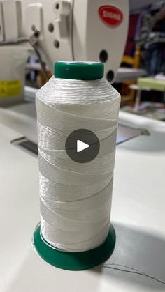 a spool of white thread sitting on top of a sewing machine