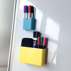 a yellow pencil holder with pens and markers on the wall next to a white door