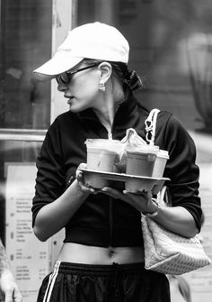 black and white photograph of a woman holding food in her hands while walking down the street