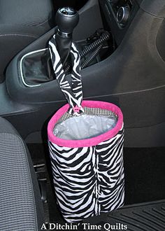 a zebra print cup holder in the front seat of a car with a pink handle