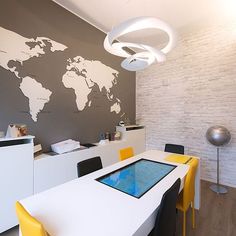 a white table with yellow chairs in front of a world map on the wall behind it