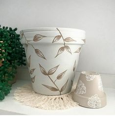 a white planter sitting next to a potted plant on top of a table