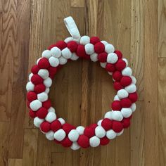 a red and white wreath with pom - poms