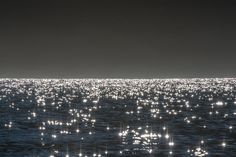 the sun shines brightly on the water as it reflects in the dark sky over the ocean