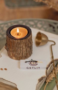 a lit candle sitting on top of a table next to a book and other items