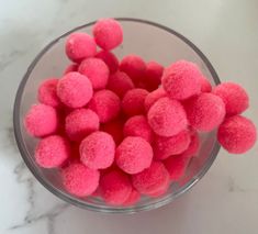 a bowl filled with pink pom - poms on top of a white counter