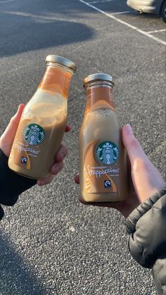 someone holding two bottles of starbucks coffee in their hands