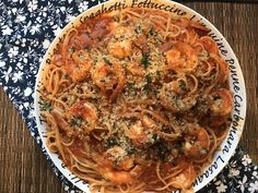 pasta with shrimp and parmesan cheese in a white bowl on a floral table cloth