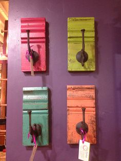 four different colored wooden hooks on a purple wall with a price tag hanging from them