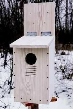 a bird house built into the side of a tree in the woods with snow on the ground