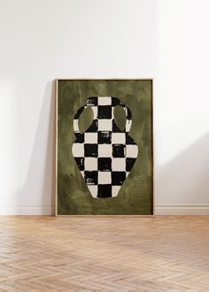 a black and white checkered vase sitting on top of a wooden floor next to a wall