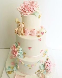 a three tiered cake with pink flowers and teddy bears on it