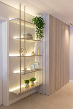 a white shelf with plants and pictures on it in front of a wall mounted bookcase