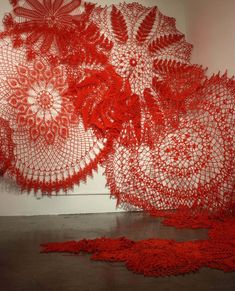 red crocheted doily on the floor in front of a wall with white walls