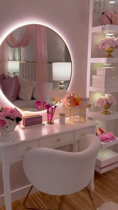 a white desk topped with a mirror next to a chair and pink flowers on top of it