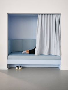 a woman laying on top of a bed under a white curtain with shoes underneath it