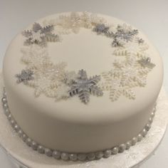 a white frosted cake with silver snowflakes on it