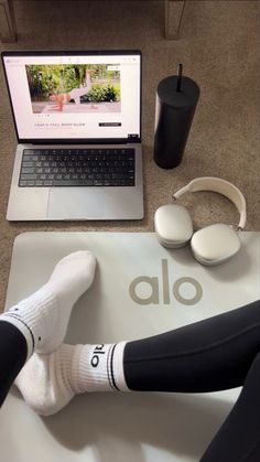 a person wearing headphones sitting in front of a laptop computer on top of a mat