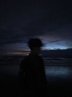 a man standing on top of a beach under a cloudy sky