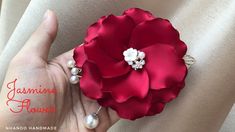 a hand holding a red flower with pearls on it