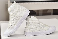 a pair of white shoes with pearls on them sitting on a table next to a piano