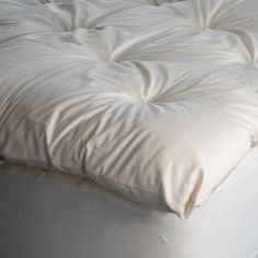 an unmade bed with white sheets and pillows