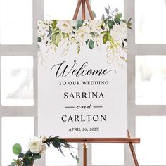 a welcome sign on an easel with flowers