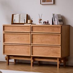 a wooden dresser sitting next to a window in a room with hardwood floors and white walls